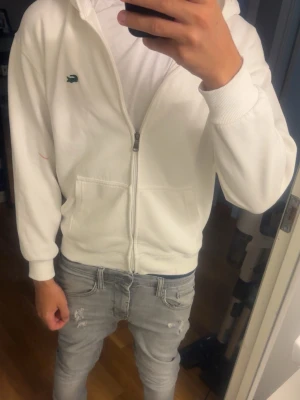 Lacoste zip up hoodie  - En Lacoste zip up hoodie. Den är i sådär skick och har några fläckar som jag är osäker om de går och få bort men om man kan få bort dom är den som ny.