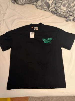 Svart Gallery Dept. t-shirt - Snygg svart t-shirt från Gallery Dept. med grönt tryck fram och bak. Klassisk passform och rund hals. Tillverkad i mjuk bomull, perfekt för en avslappnad streetwear-look.