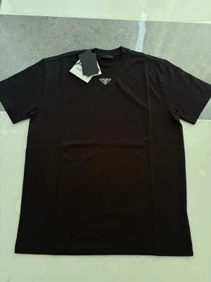 Prada t shirt  - Hej! Säljer en jätte fin T-shirt som är i väldigt bra skick inga problem alls Väldigt fin till sommaren Storlek S (lite baggy, kan även passa M) Påse och tags ingår Skriv gärna vid intresse ❤️💯