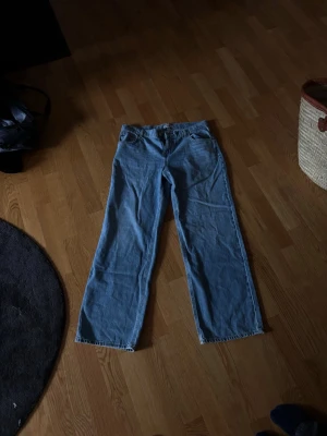 Ljusblå raka jeans - Säljer ett par ljusblå jeans med rak passform och klassisk femficksdesign. Jeansen har normal midja och är tillverkade i denim med synliga sömmar.
