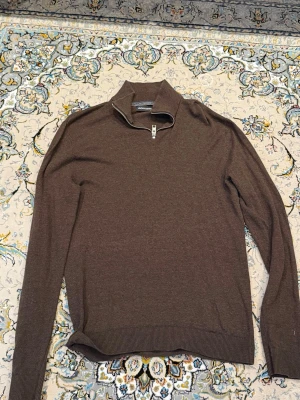 Brun quarterzip tröja med krage från Jack and Jones  - Snygg brun långärmad tröja med halvzip och hög krage. Tröjan har ribbade muddar vid ärmslut och nederkant, vilket ger en clean och stilren look. Perfekt för lager på lager och funkar till det mesta.