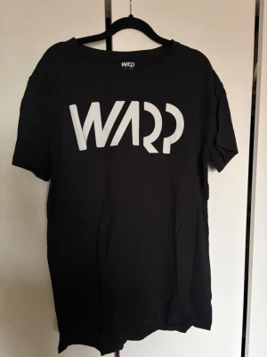 Svart t-shirt från WARP med tryck - Snygg svart t-shirt från WARP med stort vitt logotryck på bröstet. 