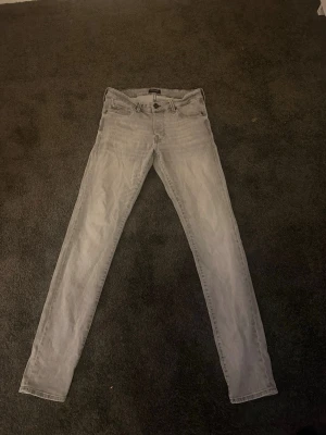 Jack&jones jeans - Säljer ett par ljusgråa  jeans med klassisk femficksdesign och dragkedjegylf. Jeansen har smal passform och raka ben, perfekta till en avslappnad stil. Materialet är mjukt denim som är väldigt bekvämt, från Jack and jones 31/34 billiga snygga jeans 