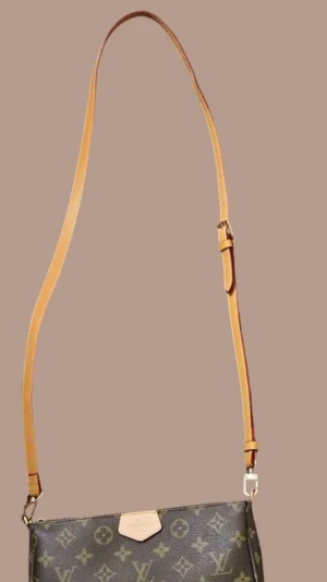 Brown adjustable bag strap -  A brown leather bag shoulder strap in new condition. Features metal hook clasps at both ends. The strap includes a buckle for length adjustment. It is well-suited for Louis Vuitton bag models, among others. The photo shows how it looks attached to a bag. Material: PU leather (polyurethane). Strap length: approximately 100 cm.