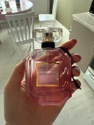 Victoria's Secret Bombshell parfym - Säljer en Victoria's Secret Bombshell Eau de Parfum. Flaskan är rosa med en elegant, multifasetterad form och har en stor, genomskinlig kork. Märkets klassiska etikett i guld och svart pryder framsidan. Perfekt för dig som gillar fräscha och feminina dofter.