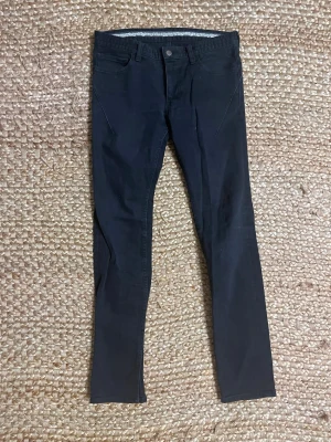 Black Number (N)ine jeans - Säljer ett par svarta skinny jeans med hög midja och smal passform. Jeansen har klassiska fem fickor, dragkedja och knapp framtill samt stretchigt material för extra komfort. Perfekta till en avslappnad eller trendig look.