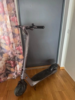 Elscooter VEEL grå - Säljer en elscooter från VEEL i snygg grå färg med svart fotplatta och handtag. Scootern har robust ram i metall och stora hjul för smidig körning. Perfekt för att ta sig runt i stan på ett snabbt och smidigt sätt.
