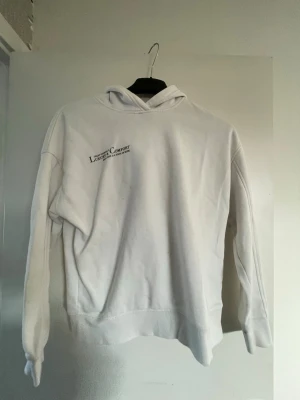 Vit hoodie från Amisu med tryck - Säljer en vit hoodie från Amisu i storlek XS. Hoodien har huva och ett diskret svart tryck på bröstet där det står 'attest youreself Luxury & comfort wellness is a start of beaing'