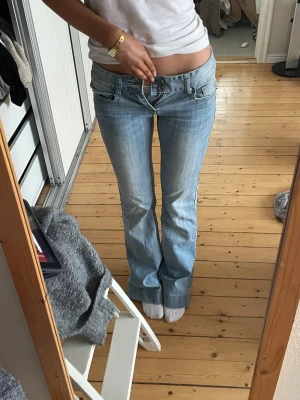 Bootcut jeans från Lochina, ljusblå - Säljer ett par ljusblå bootcut jeans från Lochina i storlek 26. Jeansen har låg midja, klassisk femficksdesign och snygga detaljer med dragkedjor på bakfickorna. Tillverkade i 100% bomull för en skön och autentisk jeanskänsla. Dom är små i storlek❤️ det är trasiga i gylfen 