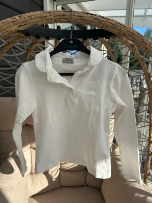Långärmad tröja 110/116 - Klassisk vit långärmad henley från Mywear med mjukt bomullstyg och knappar vid halsen. Perfekt för en clean och enkel stil. Liten fläck som syns på sista bilden, går säkert bort i tvätten.