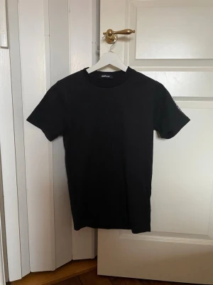 Svart t-shirt från Replay - En stilren svart t-shirt från Replay med klassisk rund hals och korta ärmar. T-shirten är enkel och passar till det mesta, tillverkad i mjukt bomullsmaterial för skön känsla. Perfekt basplagg i garderoben.