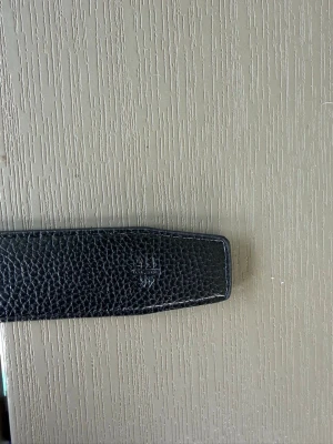 Svart skärp med metallspänne - Snyggt svart bälte i skinn med ett stort H-format metallspänne. Bältet har en stilren design med diskreta sömmar längs kanterna och en lätt texturerad yta. Perfekt för att lyfta vilken outfit som helst. ( finns många i lager ) 