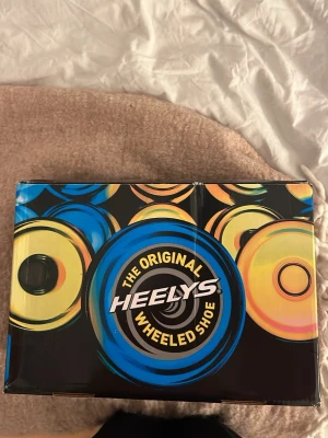 Vita Heelys sneakers med hjul - Säljer ett par klassiska vita Heelys sneakers med hjul i sulan. Skorna har en chunky sula, snörning och diskret logga på sidan. Perfekta för dig som vill rulla fram med stil! Kommer i originalkartong med instruktioner.