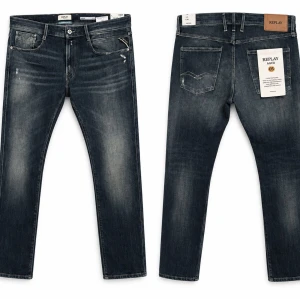 Replay Anbass Jeans - Replay Anbass Jeans – W36 L30  Replay Anbass-jeans i en snygg mörk denimtvätt med diskreta slitningar och klassiska Replay-detaljer. Modellen har en modern slim fit-passform och är lätt att matcha till både sneakers och boots.  Storlek: W36 L30 Modell: Anbass Passform: Slim fit Färg: Mörkblå denim Skick: Nyskick – mycket sparsamt använda och i utmärkt skick. Märke: Replay