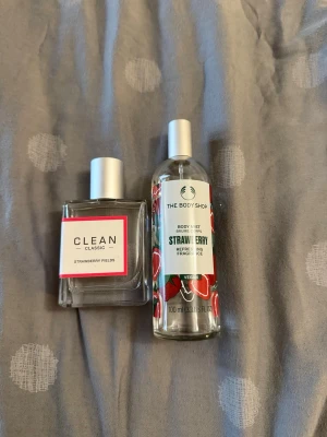 CLEAN + The Body Shop - Fräsch parfym från CLEAN Classic i doften Strawberry Fields. Flaskan är fyrkantig och genomskinlig med silverfärgad kork och rosa detaljer på etiketten. Perfekt för dig som gillar söta och bäriga dofter med en modern touch kommer med body mist. 