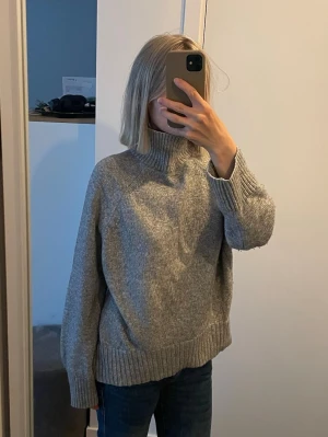 Grå stickad polotröja från HM - Mysig grå stickad polotröja från HM i storlek XS med bred ribbstickad mudd vid ärmslut och nederkant. Tröjan har en avslappnad passform och hög krage som ger extra värme. 10 kr!