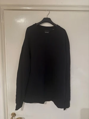 Svart sweatshirt från Jack & Jones - En enkel svart sweatshirt från Jack & Jones med rund halsringning och långa ärmar. Tröjan har en clean look utan tryck eller mönster och är tillverkad i mjukt material som passar perfekt till jeans eller joggers.