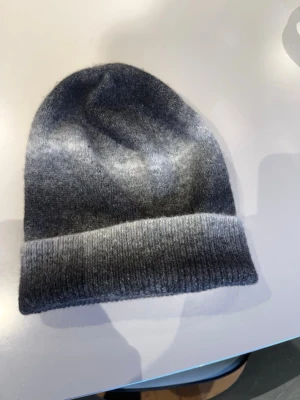 Mörkgrå ribbstickad mössa - Snygg mörkgrå mössa i ribbstickat material med uppvikt kant. Klassisk och enkel design som passar perfekt till kalla dagar. Mössan har en mjuk och stretchig känsla och är lätt att matcha med olika outfits.