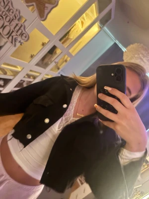 Svart cropped jeansjacka från Bershka - Säljer en svart cropped jeansjacka från Bershka med silvriga knappar och klassiska bröstfickor. Jackan har en trendig kort passform och är tillverkad i jeansmaterial. Perfekt för dig som vill ha en edgy och modern look.
