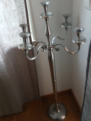 Stor silverfärgad golvljusstake - Säljer en elegant golvljusstake i metall med plats för fem ljus. Ljusstaken är silverfärgad och har klassisk, svängd design med rund fot. Perfekt som dekorativ inredningsdetalj för att skapa mysig stämning hemma. Kan silverputsa innan 