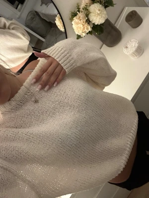 Krämvit stickad tröja - Säljer en krämvit stickad tröja med avslappnad passform och långa ärmar. Tröjan har bred ribbstickad mudd vid ärmslut och nederkant. 