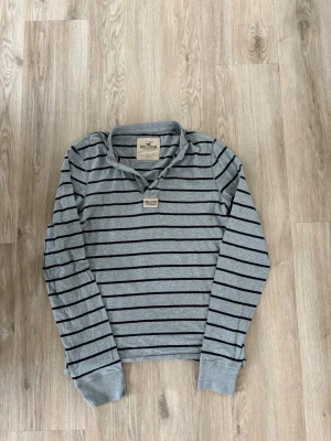 Hollister Henley ~ Sällsynt  - Säljer denna Hollister Henley i mycket bra skick och som är Sällsynt. Storlek L men kan passa M. Passar perfekt för dig som är mellan 175-180! Hör av er vid frågor eller minsta fundering 🙌  Längd: 66,5 cm  Bred: 49 cm Ärm: 72 cm