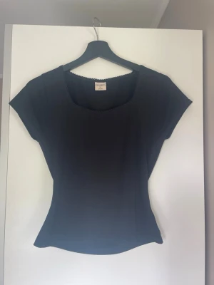 Svart topp med korta ärmar - En superfin figursydd  tshirt med spetskant vid urringningen! Köpt från gekås🫶💕