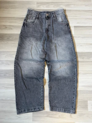 Grå baggy jeans - Säljer ett par gråa baggy jeans med bred passform och fem fickor. På baksidan finns ett rött tryck med texten 'FIVE STARS' på ena bakfickan. Jeansen har en cool, tvättad look och raka ben. Perfekta för en avslappnad streetwear-stil.