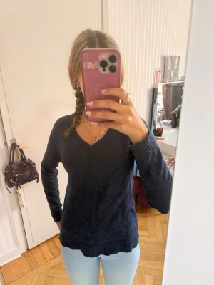 Mörkblå stickad tröja med V-ringning - Mysig mörkblå stickad tröja från VILA med V-ringad hals och långa ärmar. Tröjan har ribbstickade muddar vid ärmslut och nederkant✨