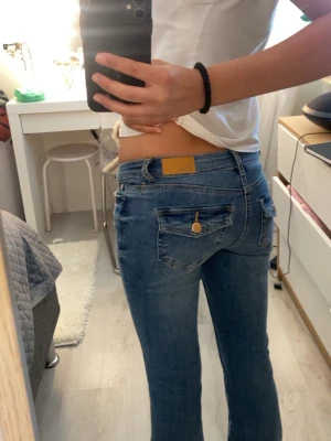 Nya Blå utsvängda low waist jeans -  Snygga blå low waist bootcut slim fit jeans med gulddetaljer på knappar och ficklock. Brukar ha strl S på jeans så om du har det hade dom förmodligen passat utan att sitta jätte tight💗