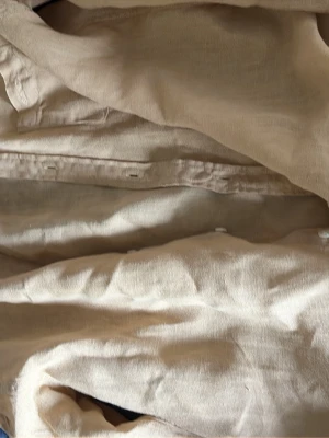 Beige linneskjorta från Gant - Säljer en stilren beige skjorta från Gant i svalt linnematerial. Skjortan har klassisk krage, knappar framtill och en avslappnad passform. Perfekt för varmare dagar och enkel att matcha med olika outfits. Kvitto finns också 
