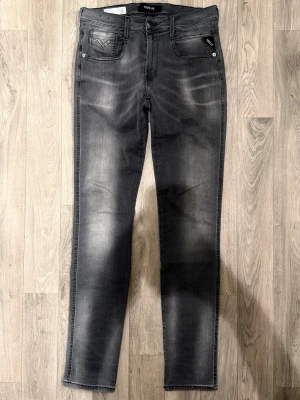Replay Anbass Hyperflex Jeans Grå W31/L34 - Slim Fit - Replay Anbass Hyperflex grå jeans i stretchig Hyperflex denim med slim fit passform som sitter snyggt och bekvämt och funkar till allt, storlek W31/L34, midja 38,5 cm, ytterbenslängd 108 cm, benöppning 15 cm, modellen är 185cm & väger 65kg, i fint skick.