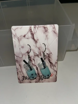 Örhängen med blå/turkos boba tea-glas - Unika örhängen formade som små glas med blå/turkos  boba tea och svarta sugrör. Finns i flera sorter/färger. Örhängens krokarna är i rostfritt stål 