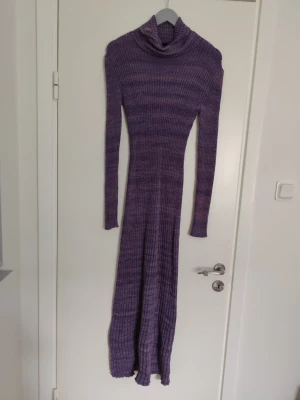 Lila ribbad långklänning Lindex - Långärmad ribbad långklänning från Lindex i en snygg lila ton. Klänningen har polokrage och är figurnära med stretchigt material som ger en bekväm passform. Perfekt för dig som gillar stickade klänningar med enkel men trendig look.