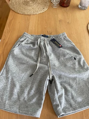 Polo Ralph Lauren shorts - Snygga grå sweatshorts från Polo Ralph Lauren med elastisk midja och snörning. Klassisk logga broderad på vänster ben och två sidofickor. Perfekta för chill dagar eller träning. Mjuk bomullskvalitet för maximal komfort. Riktigt sköna. Storlek M. Kom privat vid minsta funderingar!