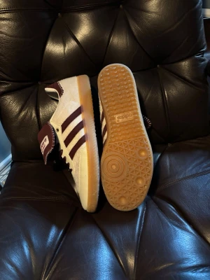 Adidas Wales Bonner - Tonal Pony - Snygga Adidas Wales Bonner sneakers i vinrött och vitt med klassiska tre ränder på sidan. Skon har en gummisula med mönster, ovandel i mocka och textil samt detaljerad sömnad på plösen. Perfekt för dig som vill sticka ut med stilrena och unika sneakers.