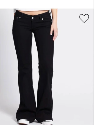 Svarta bootcut jeans med låg midja - Säljer ett par svarta bootcut jeans med låg midja och klassisk femficksmodell. Jeansen har utsvängda ben och silverfärgade knappar och nitar. Perfekta för dig som gillar en retro och avslappnad stil. Materialet ser ut att vara stretchigt denim. XS kort längd.