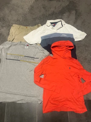 Märkespaketet Ralph Lauren & Tommy Hilfiger - Säljer ett paket med 4 st märkesplagg till ett lågt pris. Säljes i befintligt skick,  Röd RL Luvtröja: Har små hål på ärmarna (går lätt att laga själv). Så har lite mer värd i sig   Beige Cargoshorts: Litet hål vid fickan (går lätt att laga själv). Finns lite fläckar (går inte att ta bort)    Grå Tommy T-shirt: Har fläckar (går inte bort).   Vit Piké: Har missfärgning på ärmen (går inte bort).