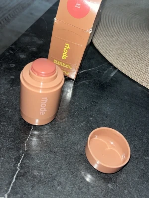Rhode Pocket Blush Tan Line - Rhode Pocket Blush i nyansen Tan Line. Krämrouge i en smidig stickform med beige-brun förpackning. Färgen är en varm, naturlig nude-ton som ger kinderna en fräsch glow. Perfekt att ha med i väskan för enkel applicering när som helst.