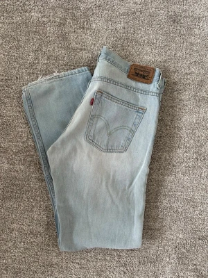 Ljusblå Levi's jeans med raka ben - Ljusblå jeans från Levi's med klassisk femficksmodell och raka ben. Jeansen har en vintagekänsla med ljus tvätt och detaljer som läderpatch bak i midjan och röd Levi's-tag på bakfickan. Tillverkade i bomull för en skön och avslappnad look.