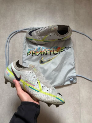 Nike Phantom GT2 Elite FG – Strl 43 ⚽️ - Säljer ett par Nike Phantom GT2 Elite i storlek 43. Använda men fortfarande i bra spelbart skick med mycket kvar att ge.  Dobbarna har bra grepp kvar och originalpåsen ingår. Skorna säljs utan skosnören. Hör gärna av dig om du har frågor eller funderingar samt bud tas emot väl!😁