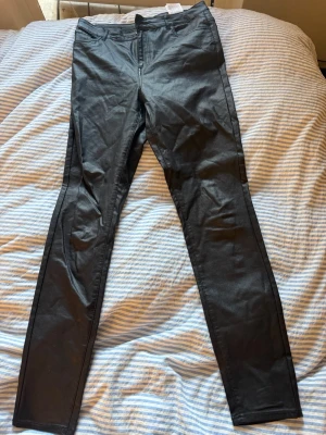 Svarta skinny jeans med hög midja - Säljer ett par svarta skinny jeans med hög midja och klassisk femficksdesign. Jeansen har smal passform och dragkedjegylf. Materialet är stretchigt och ger en snygg siluett. Perfekta till en trendig vardagslook. Vet inte riktigt storlek men skulle gissa på en L
