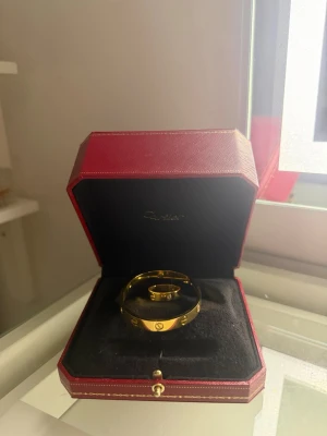 Guldigt armband  - Snyggt guldigt armband  i klassisk design med skruvdetaljer runt om. Armbandet kommer i en elegant röd ask med svart inredning och har en exklusiv känsla som verkligen sticker ut ring följer med Påse följer med!!
