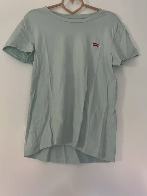 Ljusblå t-shirt från Levi's - Snygg ljusblå t-shirt från Levi's med klassisk rund hals och liten röd logotyp på bröstet. T-shirten är enkel och stilren, perfekt till jeans eller shorts. Tillverkad i mjuk bomull och har korta ärmar.