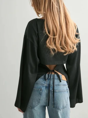 Svart satin blus med öppen rygg  - Superfin svart satin blus med öppen rygg som man knyter. Tyget är något glansigt men inte alls genomskinligt. Den är använd några gånger men fortfarande fint skick 🥰