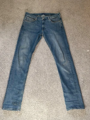Gant jeans 170cm/15 år - Säljer ett par Gant blå slim fit jeans med klassisk femficksdesign och ljusa slitningar på framsidan. Jeansen har raka ben och en läderpatch bak. Materialet är denim och passformen är small. Perfekt för dig som gillar en enkel och stilren look.