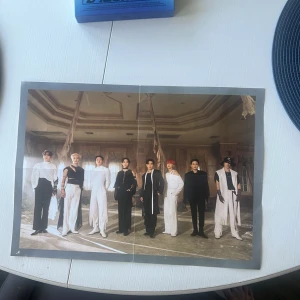  poster med A teez  - Säljer en  poster med en känd K-pop grupp. Postern visar åtta personer i svartvita outfits i ett rum med pampig inredning och trasiga gardiner. Perfekt för dig som gillar K-pop och vill ha snygg väggdekor till rummet.