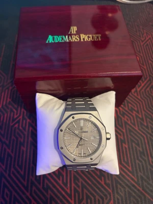 Audemars Piguet Royal Oak klocka silver - Snygg AUTOMATISK Audemars Piguet Royal Oak klocka i silver med ikonisk åttakantig boett och länkarmband i metall. Urtavlan har ett rutigt mönster och datumvisning. Kommer i exklusiv trälåda med kudde. Perfekt för dig som gillar stilrena accessoarer. 2000kr pris kan diskuteras 