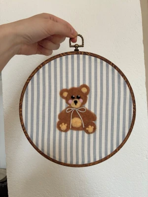 Tovad tavla nallebjörn - Rund tavla med tovad nallebjörn och blårandig bakgrund i tyg. 22cm i diameter. Perfekt för barnrummet 🧸