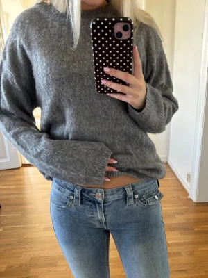 Grå stickad tröja  - Mysig grå stickad tröja med rund hals och långa ärmar. Tröjan har en enkel, klassisk design och är gjord i ett mjukt material som känns skönt mot huden. Perfekt att matcha med jeans för en avslappnad look💕.
